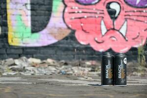 Used Montana black aerosol spray cans against graffiti paintings. MTN or Montana-cans is manufacturer of high pressure spray paint goods photo