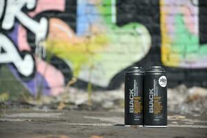 Used Montana black aerosol spray cans against graffiti paintings. MTN or Montana-cans is manufacturer of high pressure spray paint goods photo