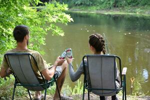 Boy and girl cheers with Budweiser Lager Alcohol Beer can during fishing. Budweiser is Brand from Anheuser-Busch Inbev most popular in America photo