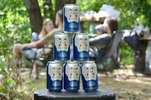 1664 Blanc logo on beer cans in big pile with fishermans on background. 1664 Blanc is the wheat beer from the French brewery Kronenbourg exported worldwide photo