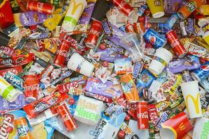 Many wrappings and cans from used products by famous worldwide brands. Pattern of trash of various colors and materials photo