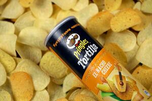 Pringles el nacho cheese flavour. Cardboard tube can on many Pringles potato chips background. Pringles is a brand of potato snack chips owned by Kellogg Company photo