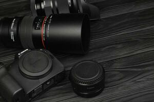 Canon EOS R photocamera and mount adapter EF - EOS R with Canon 105mm f2.8 and Sigma 24-105 f4 Art lenses on black wooden table photo