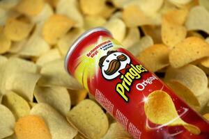 Pringles original flavour. Cardboard tube can on many Pringles potato chips background. Pringles is a brand of potato snack chips owned by the Kellogg Company photo