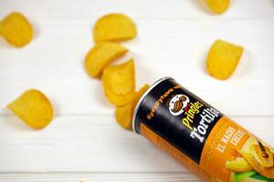 Pringles el nacho cheese flavour. Cardboard tube can with Pringles potato chips on white table. Pringles is a brand of snack chips owned by Kellogg Company photo