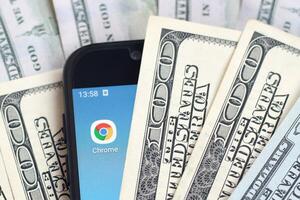 pantalla de teléfono inteligente con la aplicación google chrome y muchos billetes de cien dólares. concepto de negocios y redes sociales foto