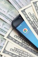 Smartphone screen with Google chrome app and lot of hundred dollar bills. Business and social networking concept photo