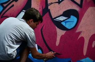 KHARKOV, UKRAINE - MAY 27, 2017 Festival of street arts. Young guys draw graffiti on portable wooden walls in the center of the city. The process of painting on walls with aerosol spray cans photo