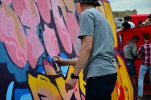 KHARKOV, UKRAINE - MAY 27, 2017 Festival of street arts. Young guys draw graffiti on portable wooden walls in the center of the city. The process of painting on walls with aerosol spray cans photo