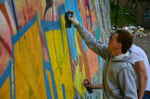 KHARKOV, UKRAINE - MAY 27, 2017 Festival of street arts. Young guys draw graffiti on an old concrete walls in the center of the city. The process of painting on walls with aerosol spray cans photo