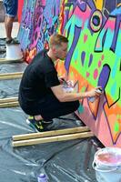 KHARKOV, UKRAINE - MAY 27, 2017 Festival of street arts. Young guys draw graffiti on portable wooden walls in the center of the city. The process of painting on walls with aerosol spray cans photo