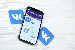 KHARKOV, UKRAINE - MARCH 5, 2021 VK icon and application from App store on iPhone 12 pro display screen on white table photo