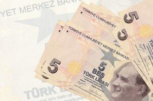 5 Turkish liras bills lies in stack on background of big semi-transparent banknote. Abstract presentation of national currency photo