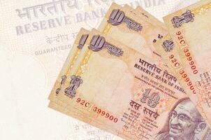 Los billetes de 10 rupias indias se encuentran apilados en el fondo de un gran billete semitransparente. presentación abstracta de la moneda nacional foto
