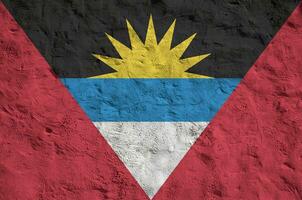 Antigua and Barbuda flag depicted in bright paint colors on old relief plastering wall. Textured banner on rough background photo