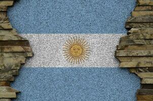 Argentina flag depicted in paint colors on old stone wall closeup. Textured banner on rock wall background photo