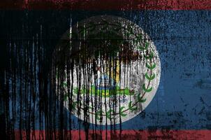 Belize flag depicted in paint colors on old and dirty oil barrel wall closeup. Textured banner on rough background photo