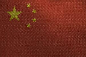 China flag depicted in paint colors on old brushed metal plate or wall closeup. Textured banner on rough background photo