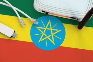 Ethiopia flag depicted on table with internet rj45 cable, wireless usb wifi adapter and router. Internet connection concept photo