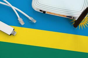 Rwanda flag depicted on table with internet rj45 cable, wireless usb wifi adapter and router. Internet connection concept photo