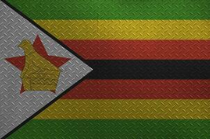 Zimbabwe flag depicted in paint colors on old brushed metal plate or wall closeup. Textured banner on rough background photo