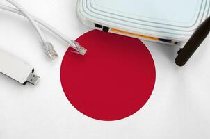 Japan flag depicted on table with internet rj45 cable, wireless usb wifi adapter and router. Internet connection concept photo