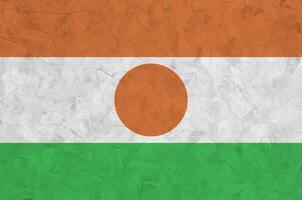 Niger flag depicted in bright paint colors on old relief plastering wall. Textured banner on rough background photo