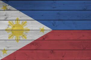 Filipinas bandera representado en brillante pintar colores en antiguo de madera pared. texturizado bandera en áspero antecedentes foto