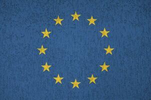 European union flag depicted in bright paint colors on old relief plastering wall. Textured banner on rough background photo