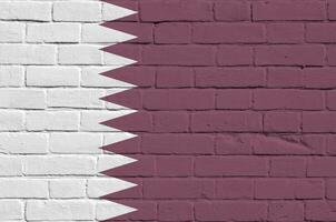 bandera de qatar representada en colores de pintura en la pared de ladrillo antiguo. banner texturizado sobre fondo de mampostería de pared de ladrillo grande foto