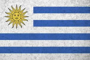 Uruguay flag depicted in bright paint colors on old relief plastering wall. Textured banner on rough background photo
