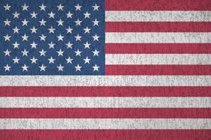 United States of America flag depicted in bright paint colors on old relief plastering wall. Textured banner on rough background photo