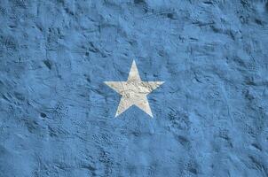 Somalia flag depicted in bright paint colors on old relief plastering wall. Textured banner on rough background photo