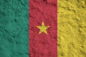 Cameroon flag depicted in bright paint colors on old relief plastering wall. Textured banner on rough background photo