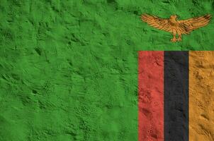 Zambia flag depicted in bright paint colors on old relief plastering wall. Textured banner on rough background photo