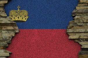 bandera de liechtenstein representada en colores de pintura en el primer plano de la pared de piedra antigua. banner texturizado sobre fondo de pared de roca foto