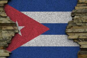 Cuba flag depicted in paint colors on old stone wall closeup. Textured banner on rock wall background photo