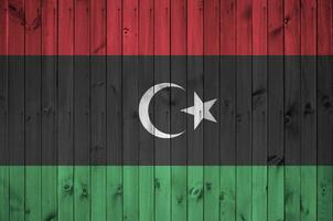 Libya flag depicted in bright paint colors on old wooden wall. Textured banner on rough background photo