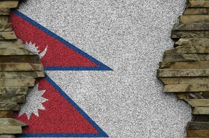 Nepal flag depicted in paint colors on old stone wall closeup. Textured banner on rock wall background photo