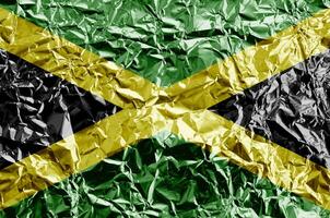 Jamaica flag depicted in paint colors on shiny crumpled aluminium foil closeup. Textured banner on rough background photo