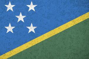 Solomon Islands flag depicted in bright paint colors on old relief plastering wall. Textured banner on rough background photo