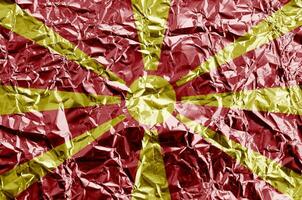 Macedonia flag depicted in paint colors on shiny crumpled aluminium foil closeup. Textured banner on rough background photo