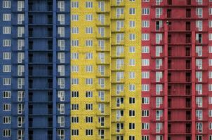 Romania flag depicted in paint colors on multi-storey residental building under construction. Textured banner on brick wall background photo