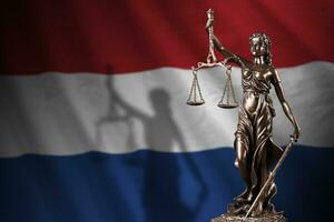 Netherlands flag with statue of lady justice and judicial scales in dark room. Concept of judgement and punishment photo