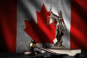 Canada flag with statue of lady justice, constitution and judge hammer on black drapery. Concept of judgement and guilt photo