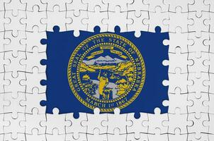Nebraska US state flag in frame of white puzzle pieces with missing central part photo