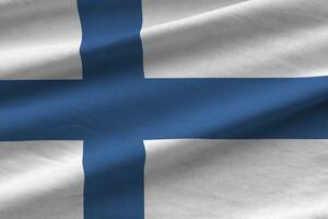 Finland flag with big folds waving close up under the studio light indoors. The official symbols and colors in banner photo