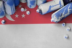 Singapore flag and few used aerosol spray cans for graffiti painting. Street art culture concept photo