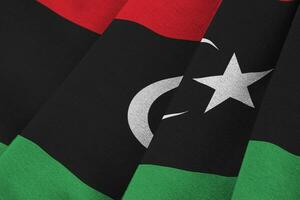 Libya flag with big folds waving close up under the studio light indoors. The official symbols and colors in banner photo