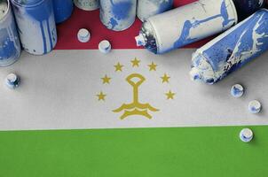 Tajikistan flag and few used aerosol spray cans for graffiti painting. Street art culture concept photo